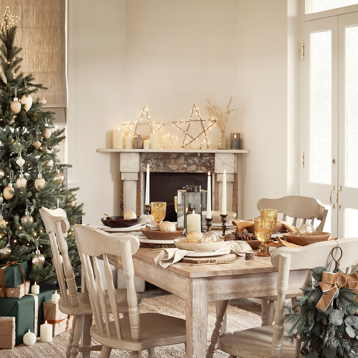 Esszimmer mit Weihnachtsbaum, gedecktem Tisch und beleuchtetem Holzstern über Kaminsims