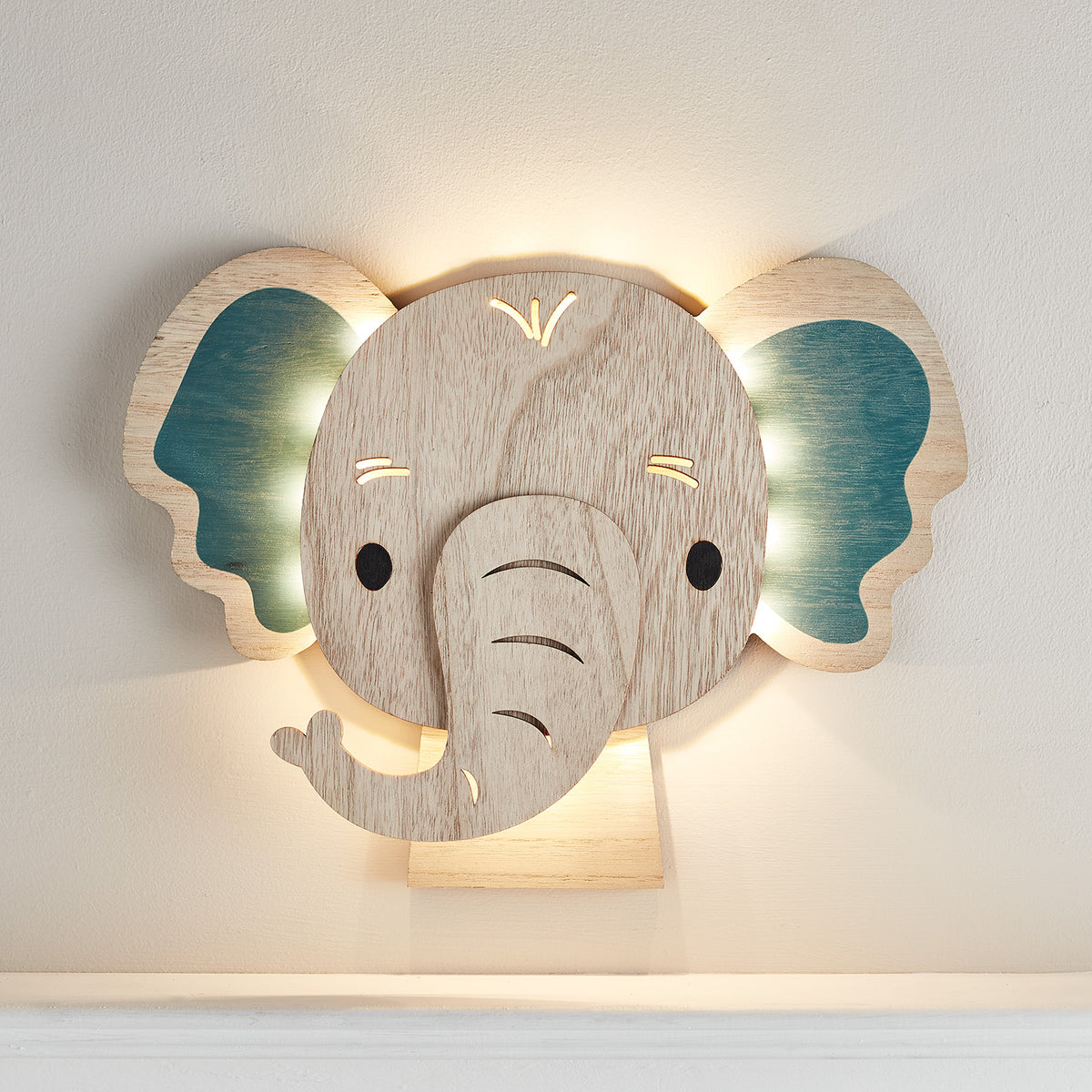 Elefanten Wandlampe aus Holz mit eingeschalteten warmweißen LEDs an der Wand