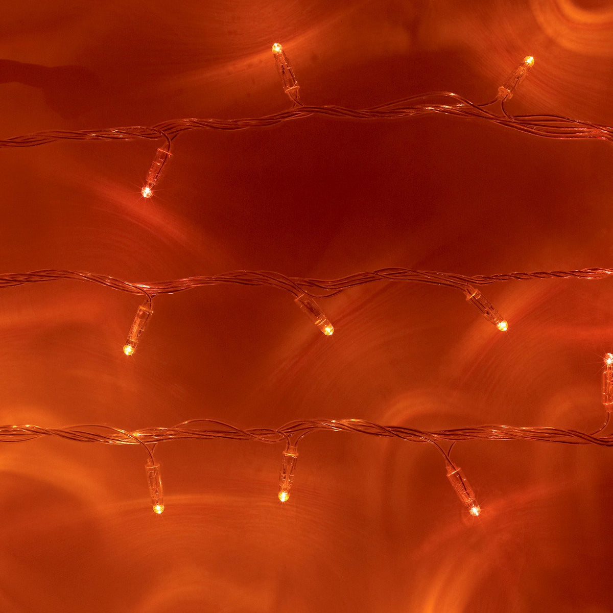 Zwei Reihen orangefarbener LED-Lichterketten mit transparentem Kabel auf orangefarbenem Hintergrund