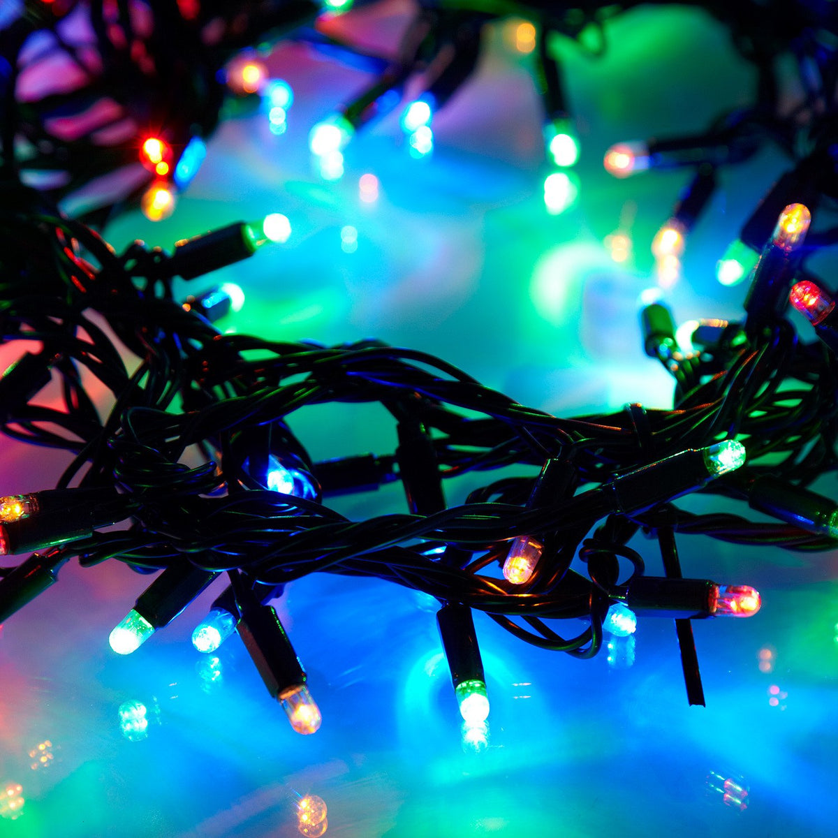 Nahaufnahme bunter LED-Lichter auf grünem Kabel mit leuchtendem Hintergrund in Blau und Grün