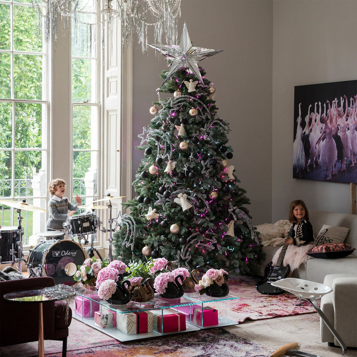 Weihnachtsbaum mit pink leuchtender LED Lichterkette in Wohnzimmer mit Kindern und Musikinstrumenten