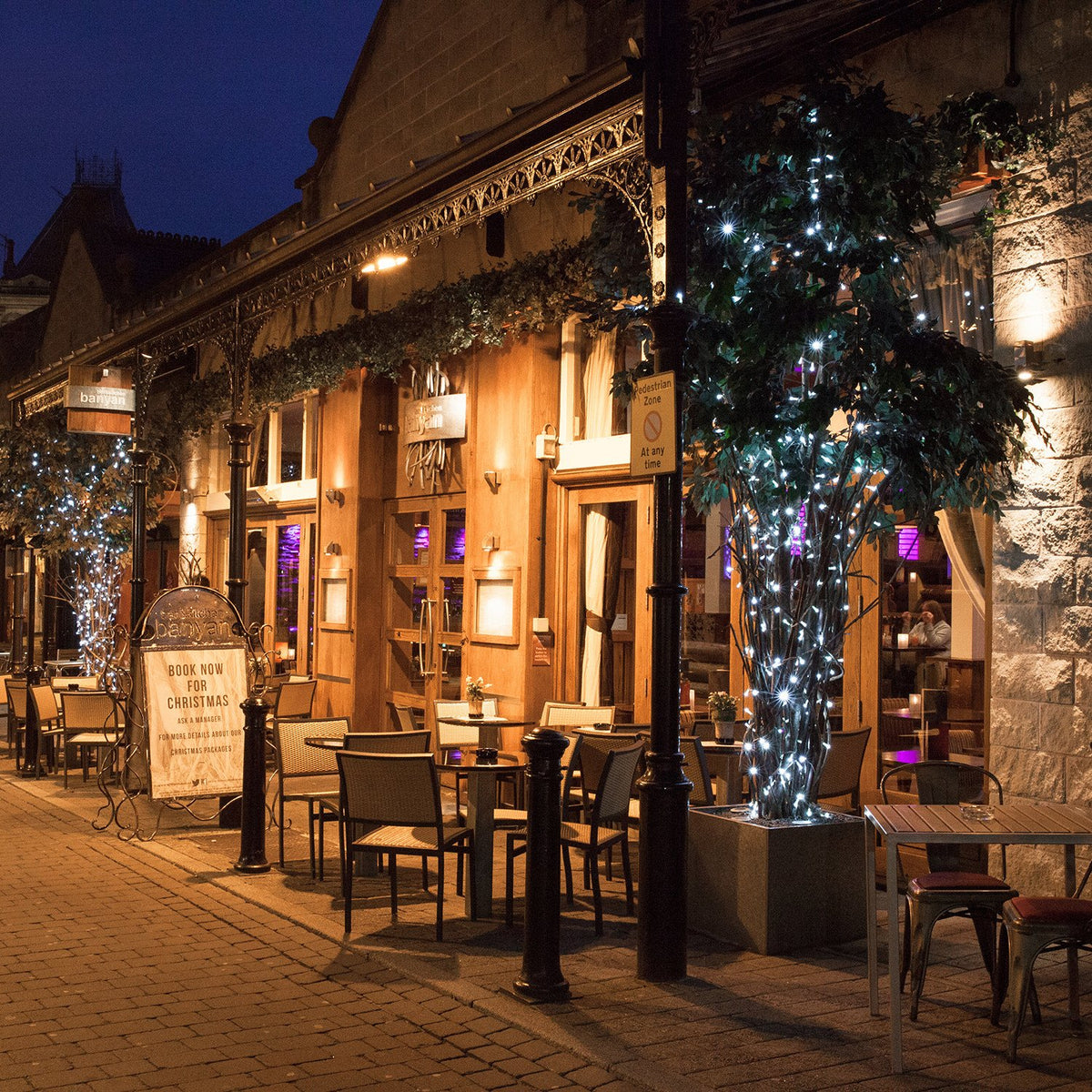 Außenbereich eines Restaurants mit Bäumen, die mit weißer LED-Lichterkette beleuchtet sind