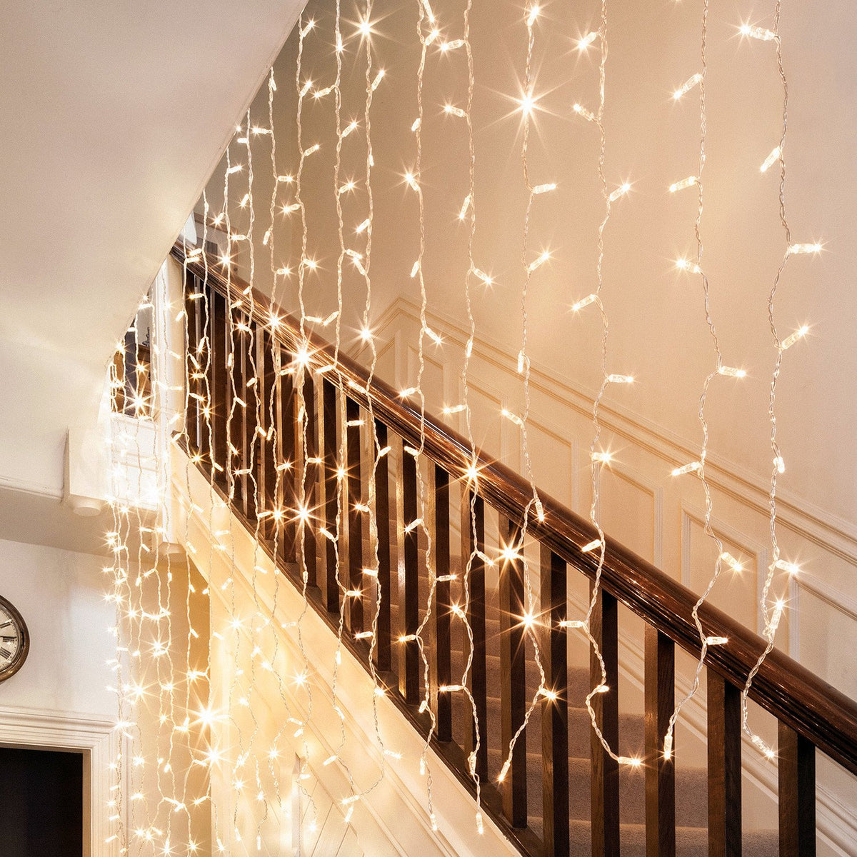 Warmweißer LED-Lichtervorhang mit transparentem Kabel an einer Treppe innen