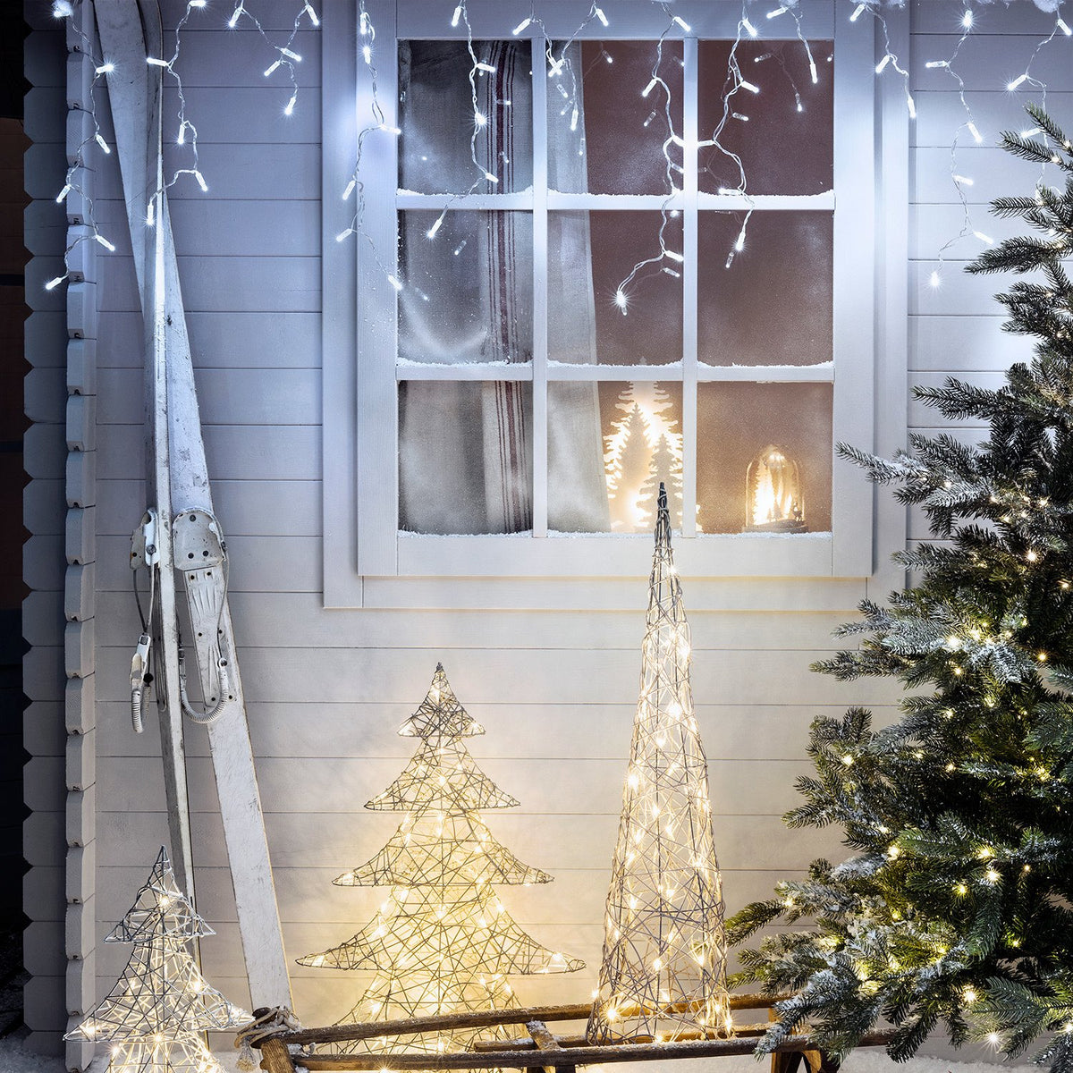 Winterliche Dekoration mit LED Eiszapfen Lichterkette, beleuchteten Drahtbäumen und Schnee