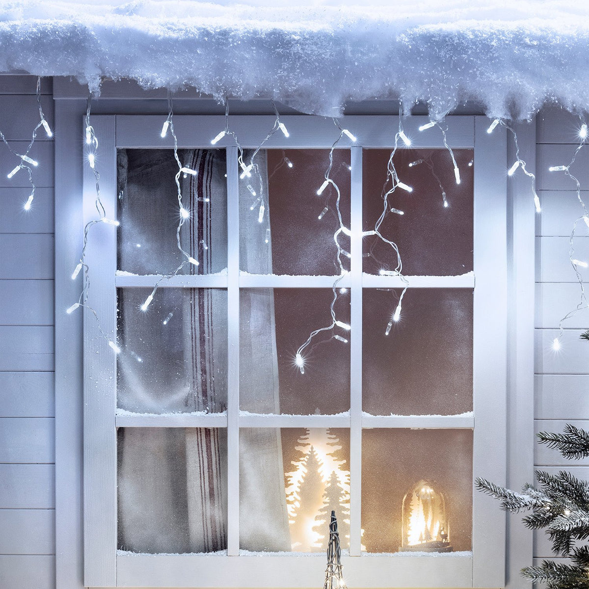 Weiße LED Eiszapfen Lichterkette dekorativ an Fenster mit Schnee und Weihnachtsdeko