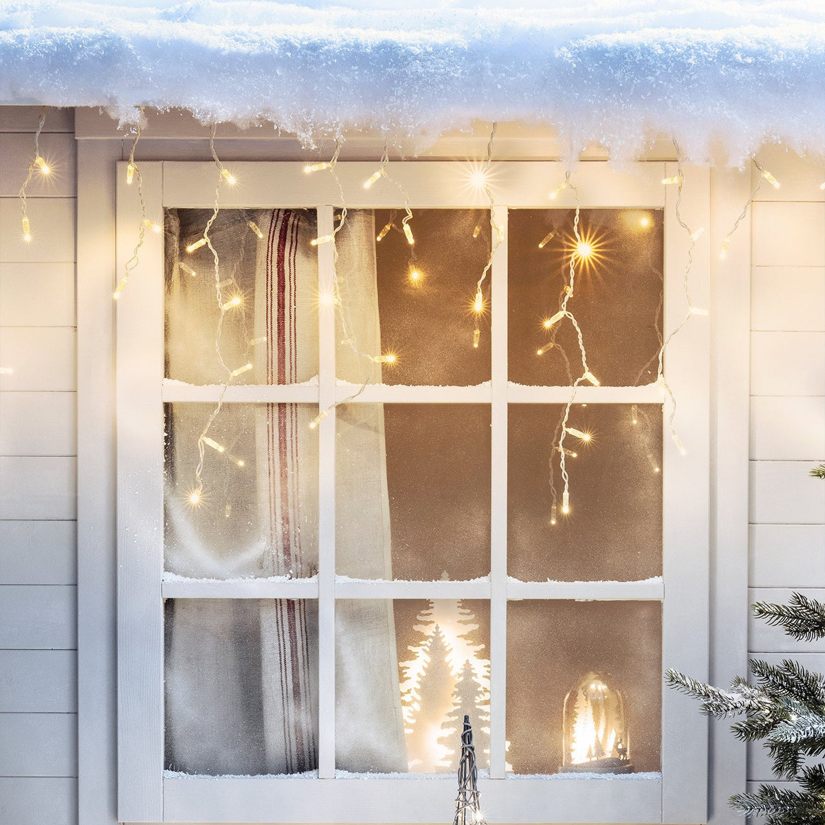 Fenster mit Schnee und warmweißer LED Eiszapfen Lichterkette dekoriert
