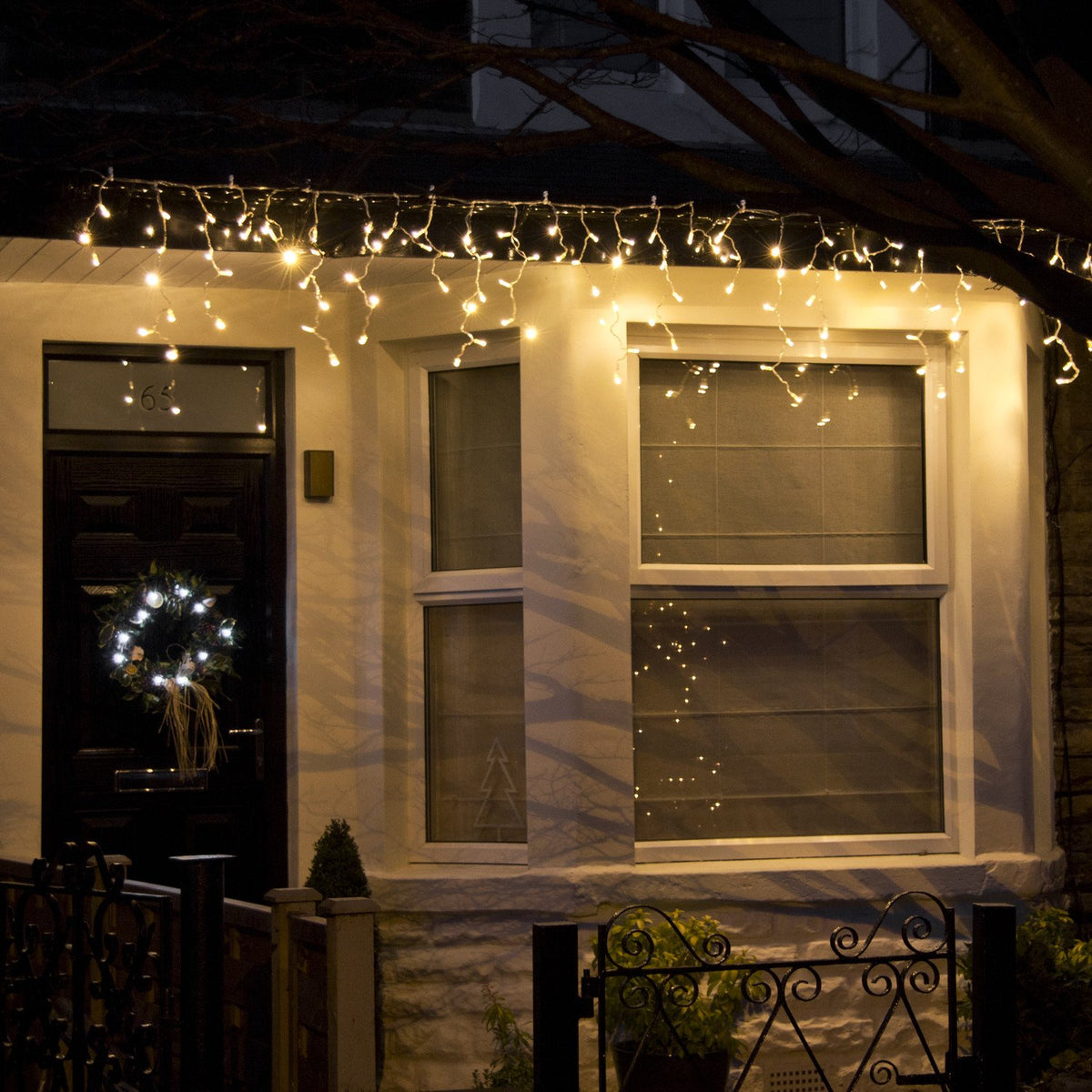 Hausfront mit warmweißer Eiszapfen Lichterkette an Dachrinne beleuchtet