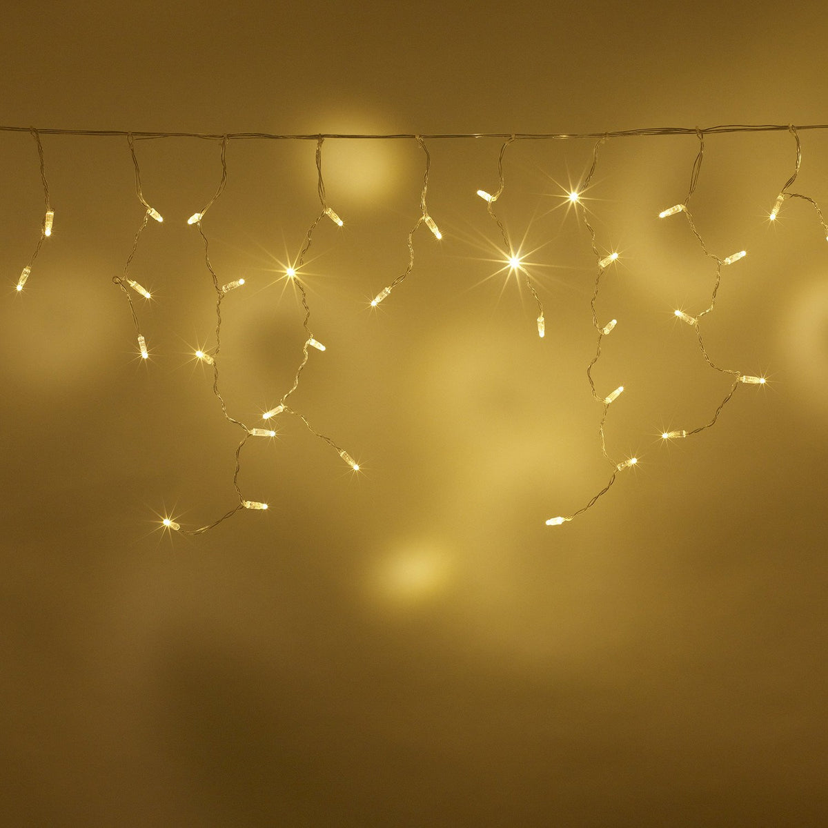 Warmweiße LED Eiszapfen Lichterkette vor gelbem Hintergrund hängend