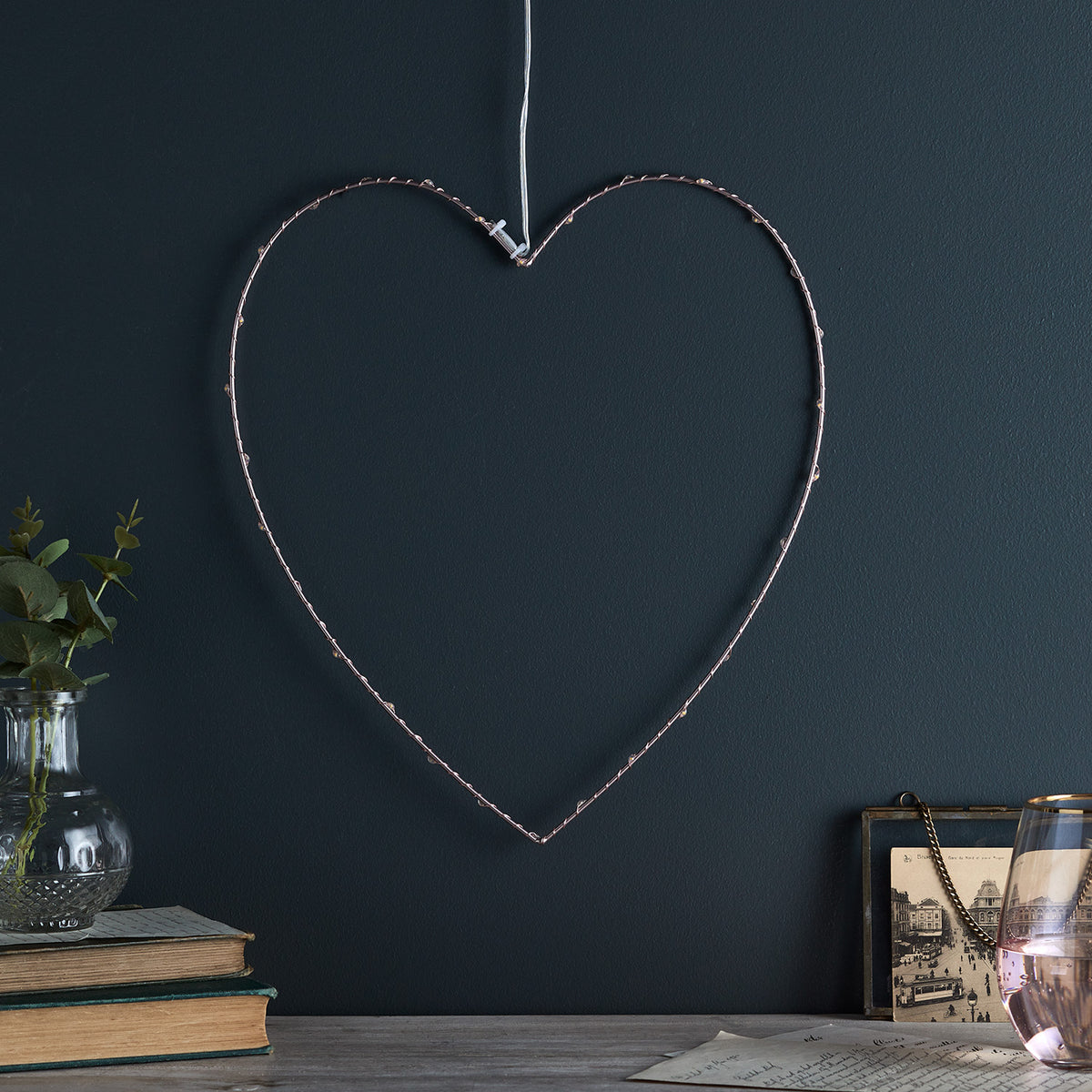 Roségoldenes Metallherz mit Micro LEDs ohne Beleuchtung vor dunkler Wand