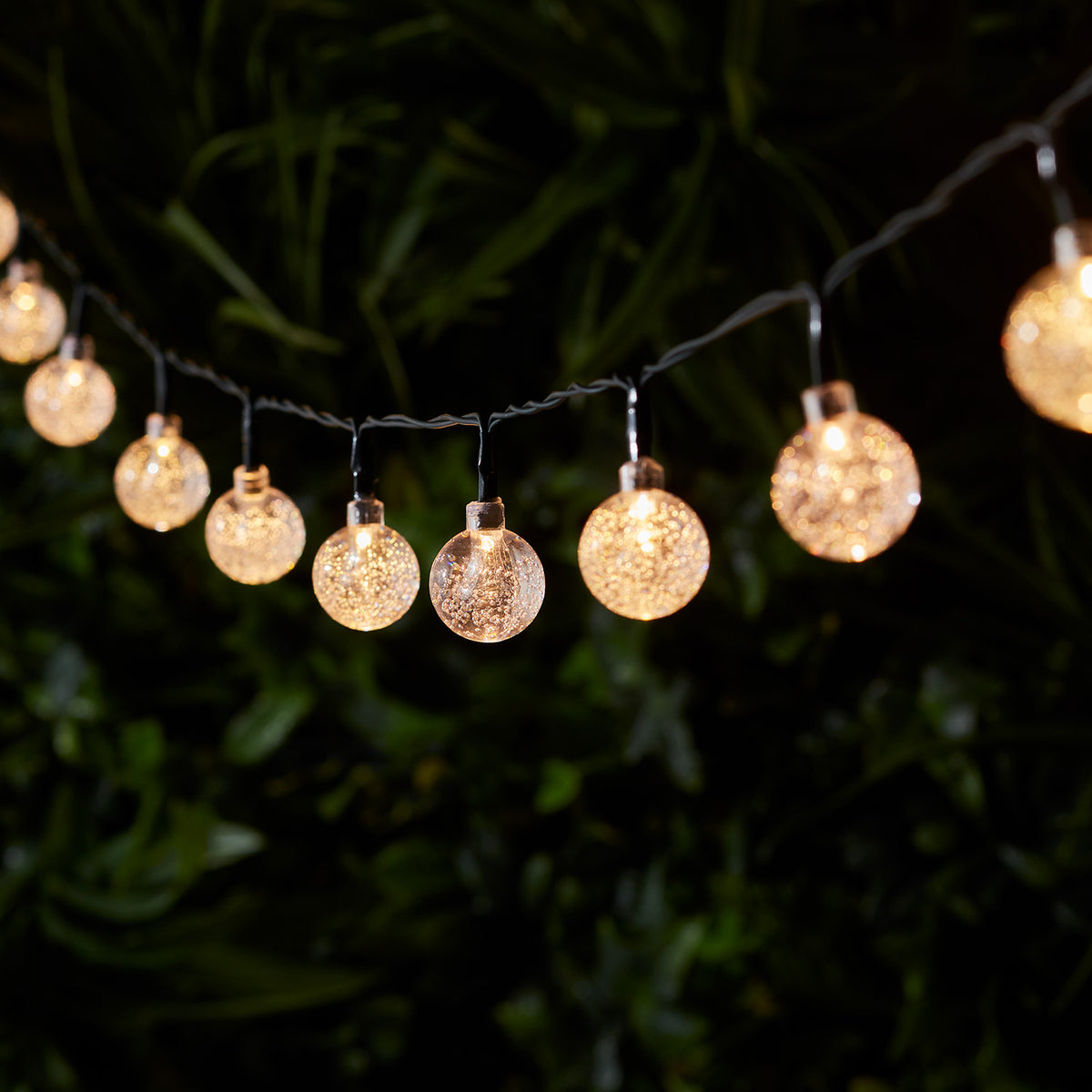 Solarbetriebene Lichterkette mit 40 warmweißen LED-Bubble-Bällen an grünem Kabel im Dunkeln