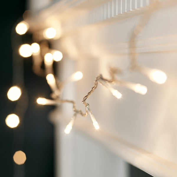 Nahaufnahme einer warmweißen LED-Lichterkette an einem weißen Kaminsims