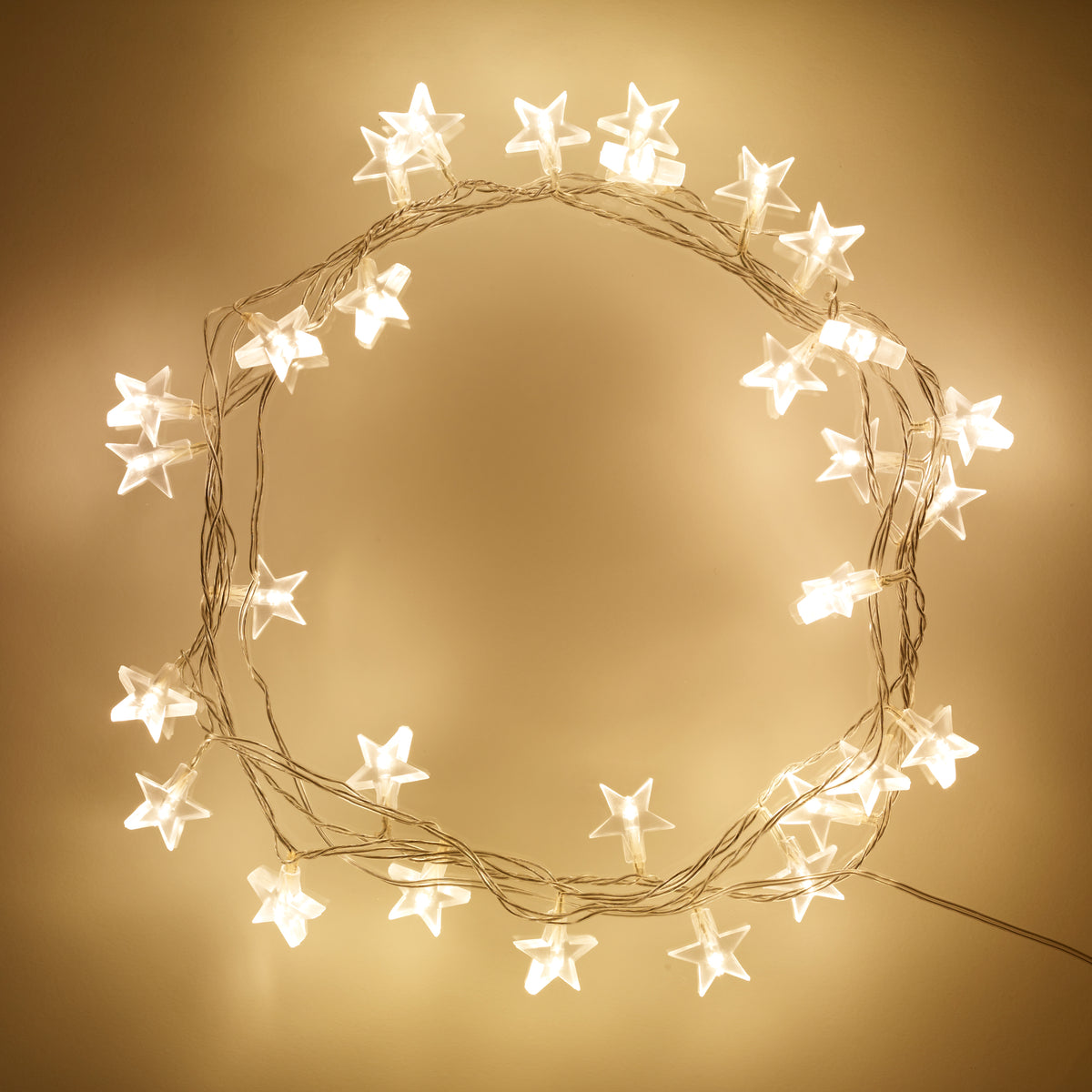 Warmweiße LED Lichterkette mit transparenten Sternen auf beige Hintergrund