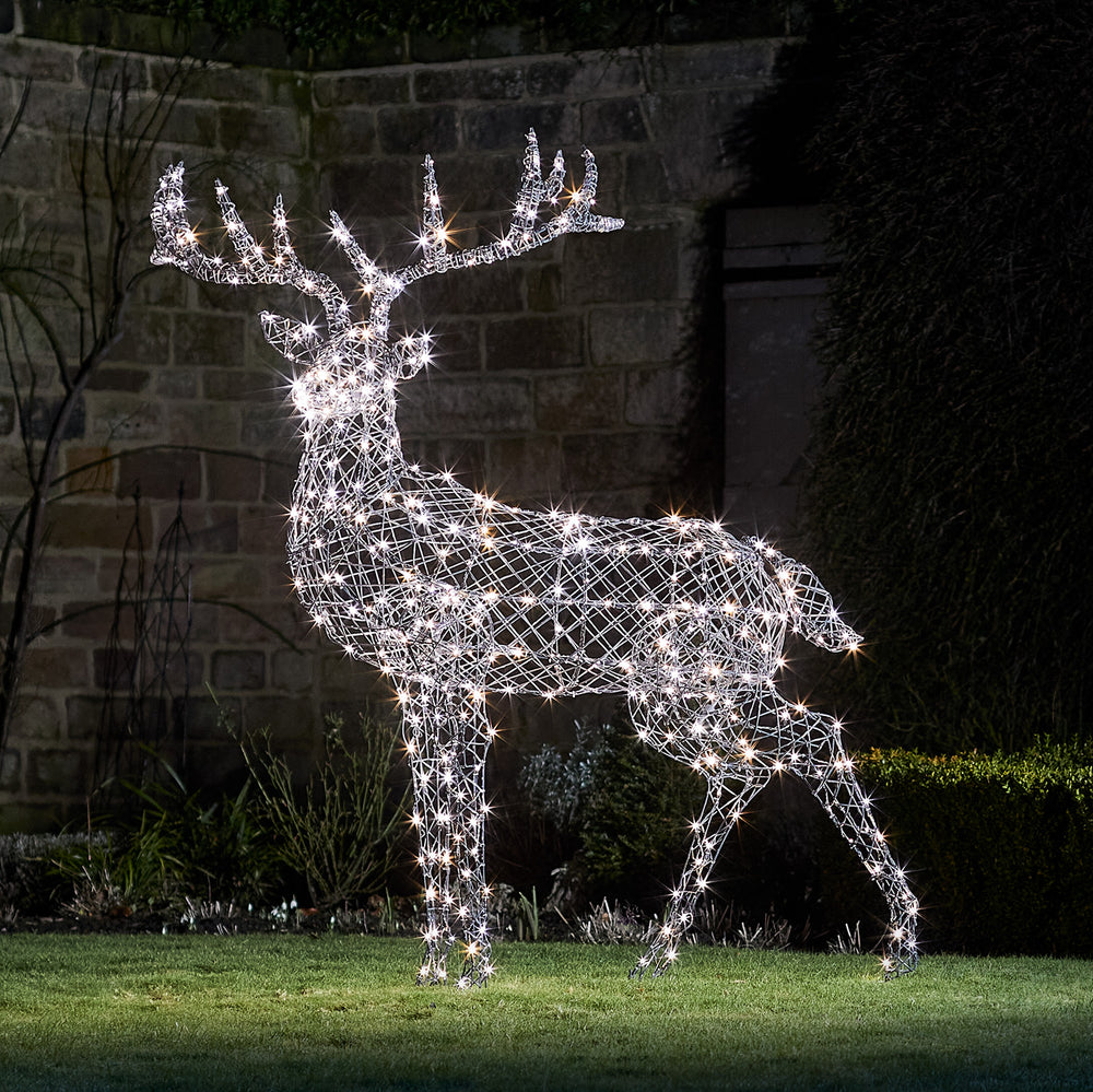 Große LED Rentierfigur mit weiß leuchtenden Lichtern aus Rattanoptik im Garten bei Nacht